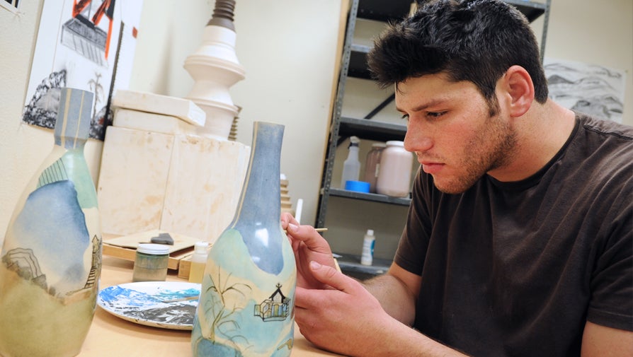 ceramics student painting vase